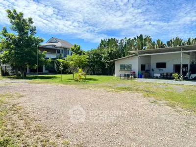 Spacious property with lush greenery and two buildings under a clear blue sky.