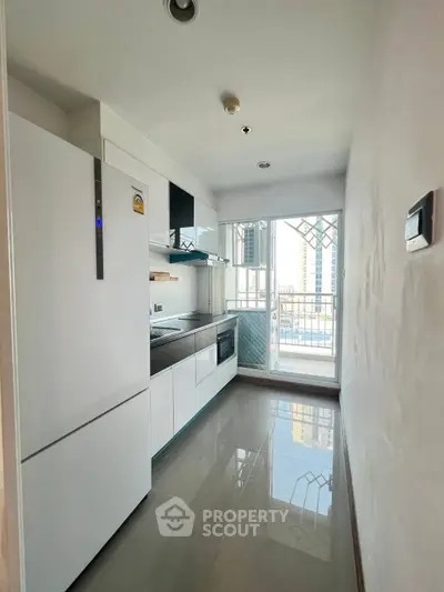 Modern kitchen with sleek appliances and balcony view in urban apartment