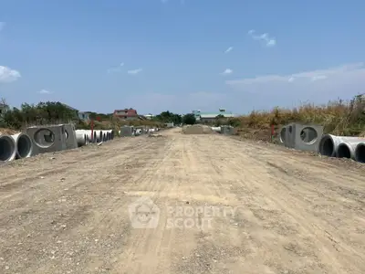 Expansive land development site with construction materials under a clear blue sky.