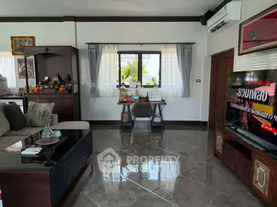 Spacious living room with modern decor and large TV, featuring elegant furniture and natural light.
