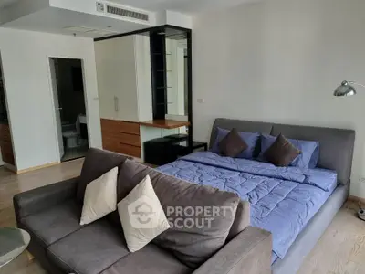 Spacious bedroom with modern decor and cozy seating area in a stylish apartment.