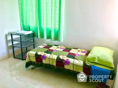 Cozy and bright bedroom with a single bed, vibrant bedspread, and sheer green curtains, perfect for restful nights in a compact living space.