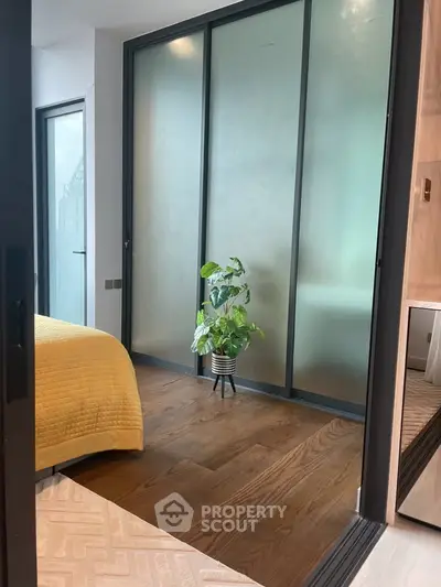 Modern bedroom with frosted glass sliding doors and wooden flooring