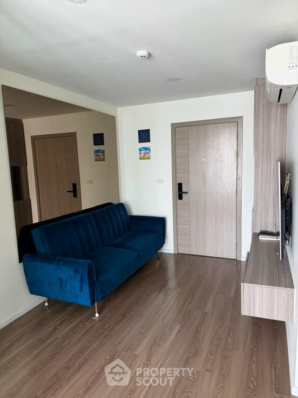 Modern living room with blue velvet sofa and sleek wooden flooring