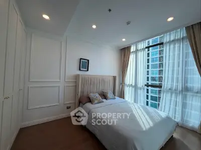 Spacious bedroom with large windows and elegant decor in modern apartment.