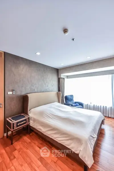 Spacious bedroom with elegant wooden flooring and large window for natural light.