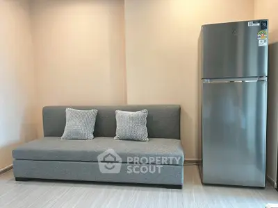 Modern living room with sleek gray sofa and stainless steel refrigerator, perfect for urban living.