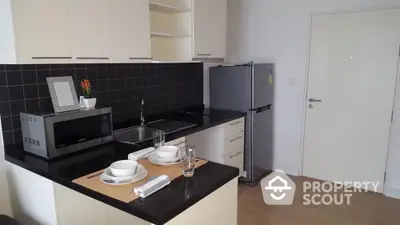 Modern kitchen with sleek black countertops and stainless steel appliances in a stylish apartment.