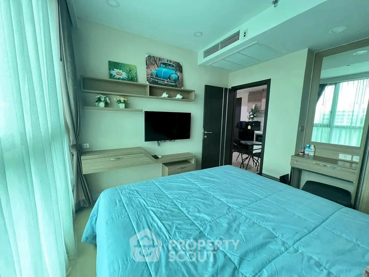 Modern bedroom with blue bedding, wall-mounted TV, and stylish decor in a bright apartment.