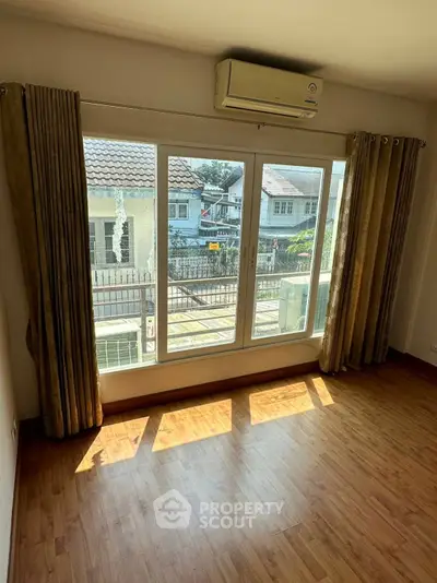 Bright empty room with large windows and wooden flooring, perfect for customization.