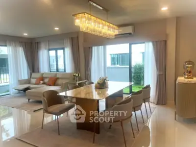 Luxurious open-plan living and dining area with elegant chandelier and modern furniture.