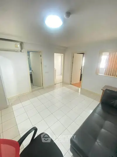 Spacious living room with tiled flooring and modern furnishings in a bright apartment.