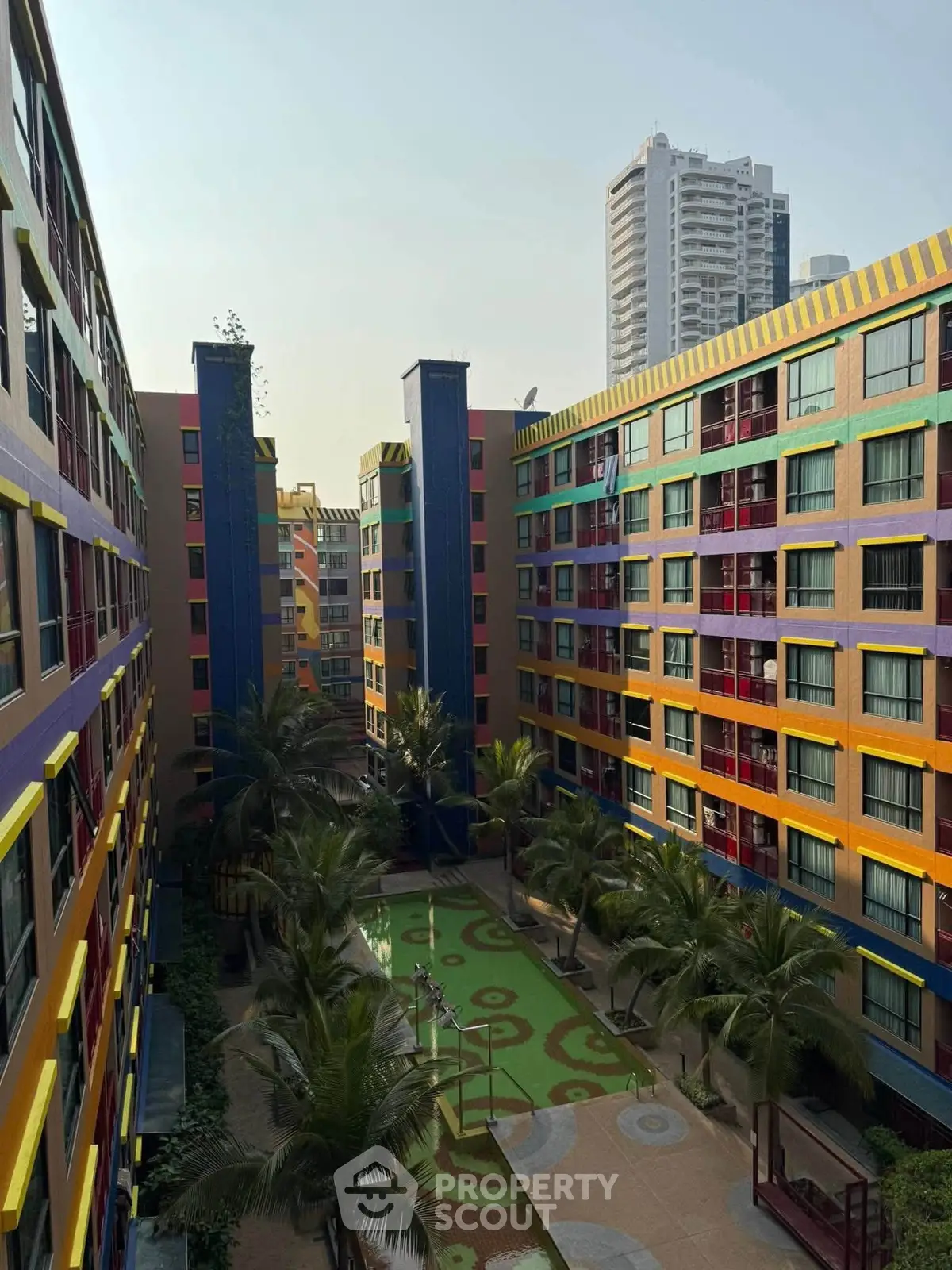 Vibrant multicolored apartment complex with lush courtyard and modern urban backdrop.