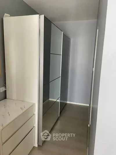 Spacious walk-in closet with sleek mirrored wardrobe doors and modern design.