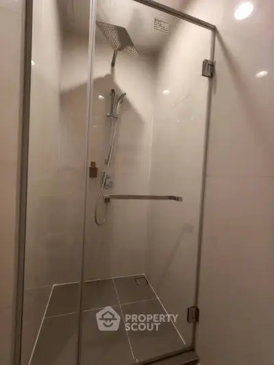 Modern bathroom with sleek glass shower enclosure and rainfall showerhead.