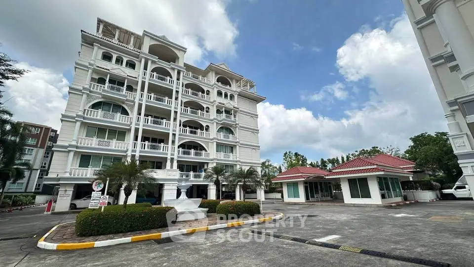Elegant white residential building with classic architecture and landscaped entrance.