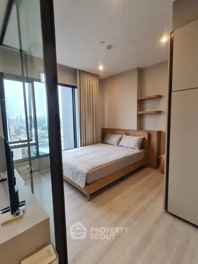 Modern bedroom with city view, featuring a cozy bed and sleek wooden flooring.