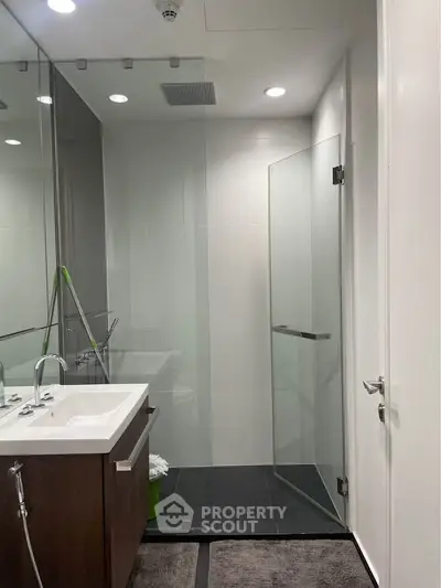 Modern bathroom with sleek glass shower and elegant vanity in contemporary home.