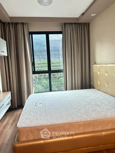 Cozy bedroom with large window and modern furnishings in a stylish apartment.