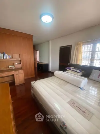 Spacious bedroom with wooden flooring and ample natural light