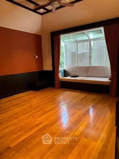 Spacious living room with hardwood floors and a cozy window seat, perfect for relaxation.