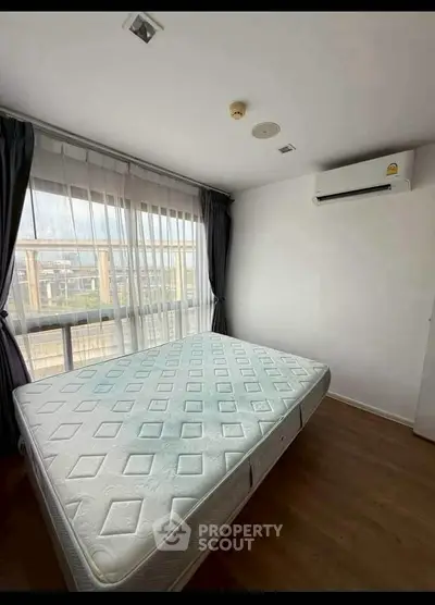Spacious bedroom with large window and air conditioning in modern apartment.