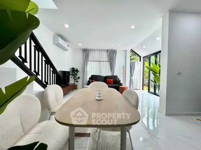 Modern living room with open layout, stylish furniture, and large windows offering garden views.