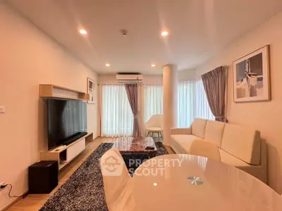 Spacious modern living room with elegant decor and large TV, perfect for relaxation and entertainment.