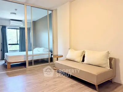 Modern apartment interior with cozy living room and bedroom separated by glass doors.