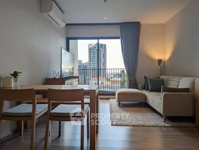 Modern living room with city view, stylish furniture, and natural light.