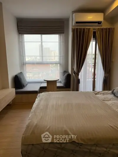 Cozy bedroom with city view, featuring a comfortable bed and stylish window seating area.