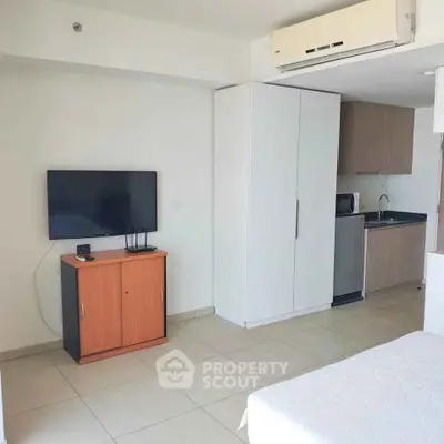 Modern studio apartment with sleek kitchenette and wall-mounted TV, perfect for urban living.
