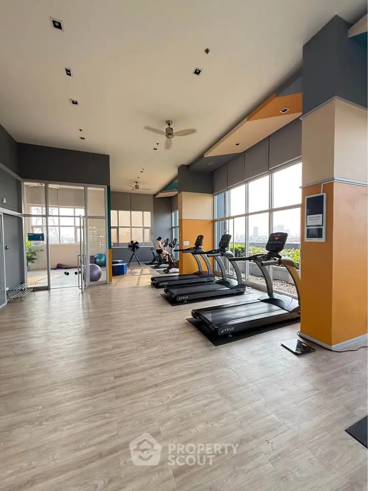 Spacious modern gym with treadmills and large windows offering city views.
