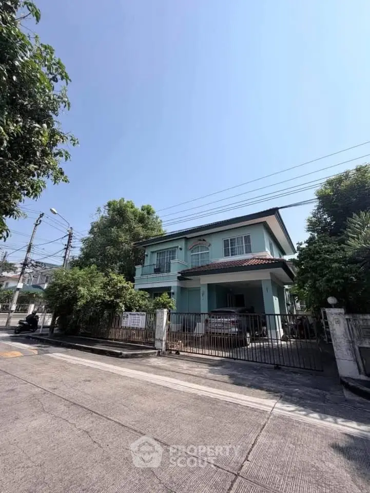 Charming two-story house with gated entrance and lush greenery in a serene neighborhood.