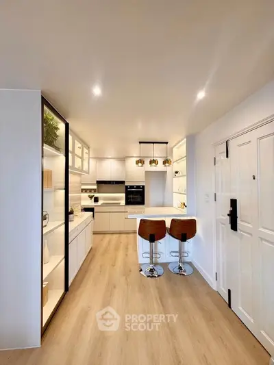 Modern kitchen with sleek design, featuring an open layout and stylish bar stools, perfect for contemporary living.