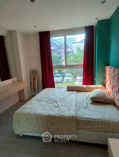Cozy bedroom with large window and floral headboard, offering a serene view.