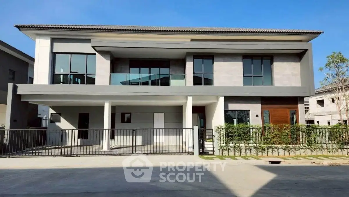 Modern two-story house with sleek design and large windows in a suburban neighborhood.