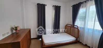 Spacious bedroom with natural light and elegant wooden furniture, perfect for a cozy and serene living experience.