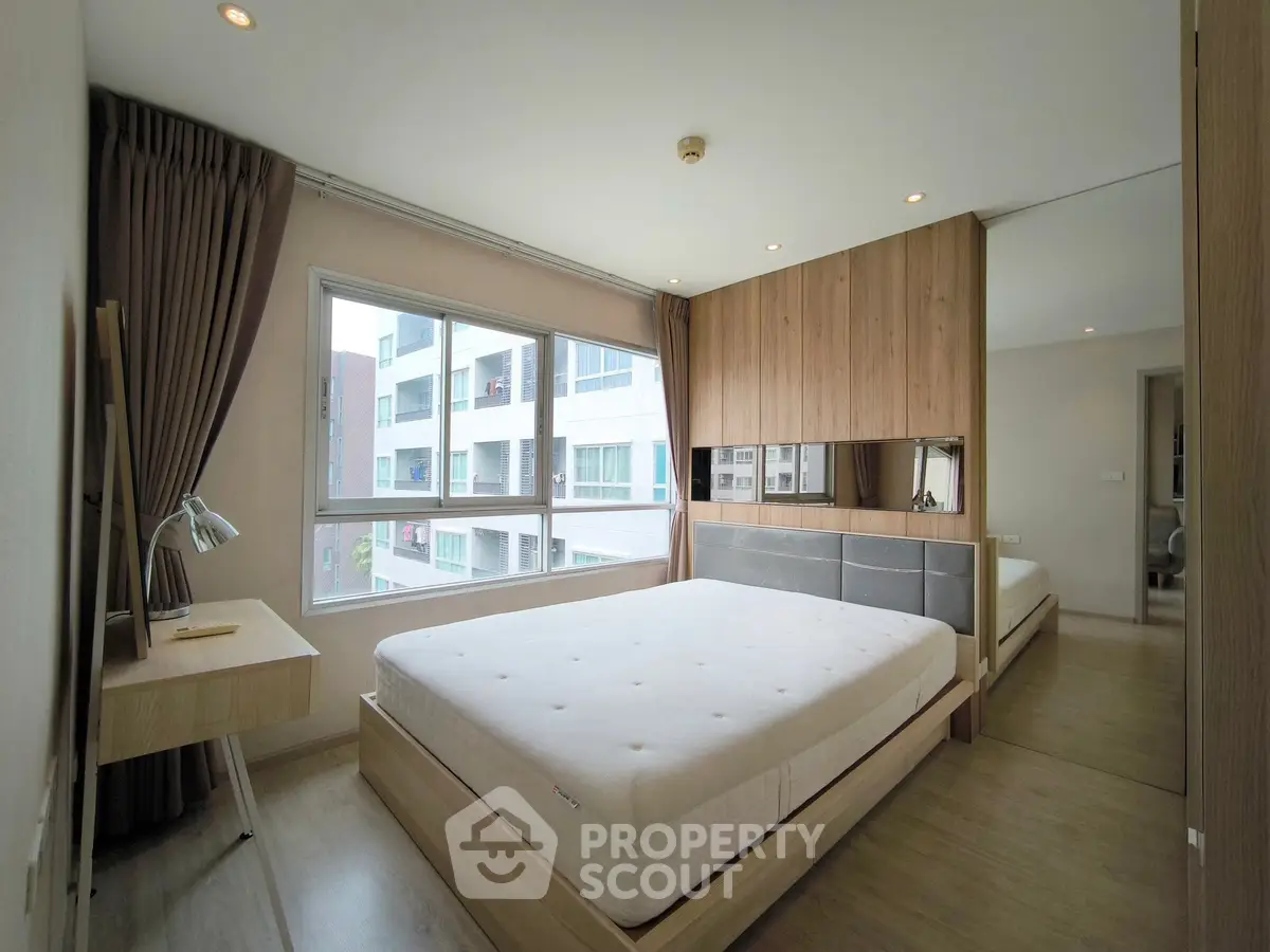 Modern bedroom with large window and stylish wooden furniture