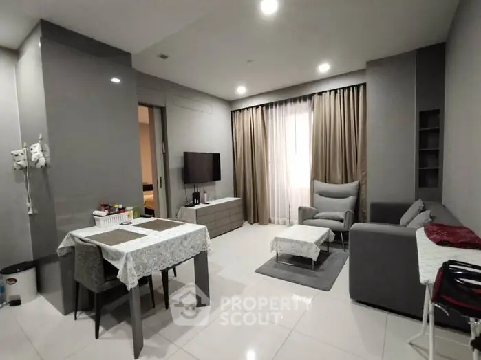 Modern living room with sleek furniture and dining area in open layout.