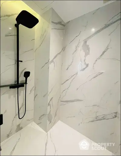 Luxurious modern bathroom with sleek marble tiles and elegant black shower fixtures.