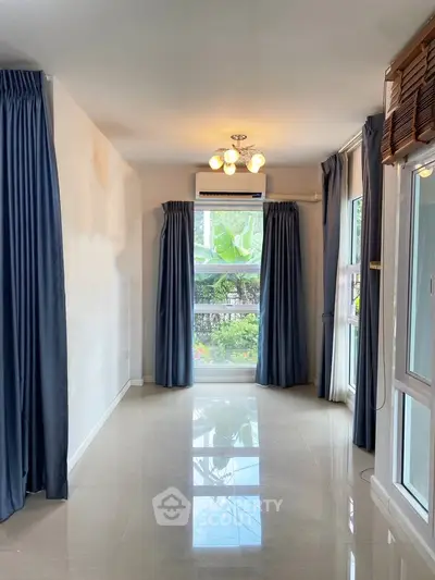 Spacious living room with large windows and elegant curtains, offering a bright and airy atmosphere.