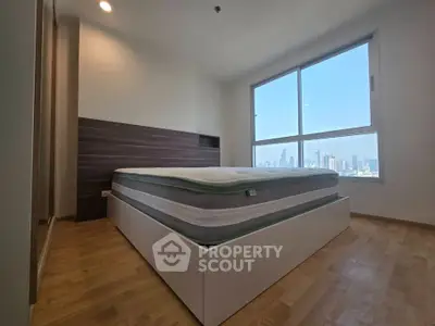Spacious bedroom with large window offering stunning city skyline views.