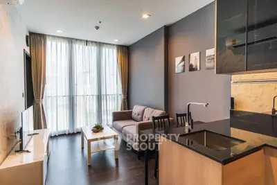 Modern living room with sleek kitchen, cozy sofa, and large windows for natural light.