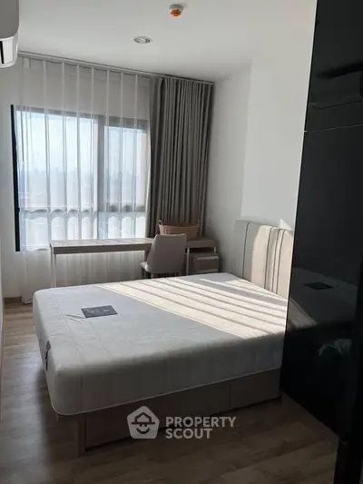 Modern bedroom with large window and stylish furniture, perfect for urban living.