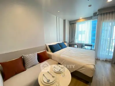 Modern bedroom with cozy seating area and large windows offering city views