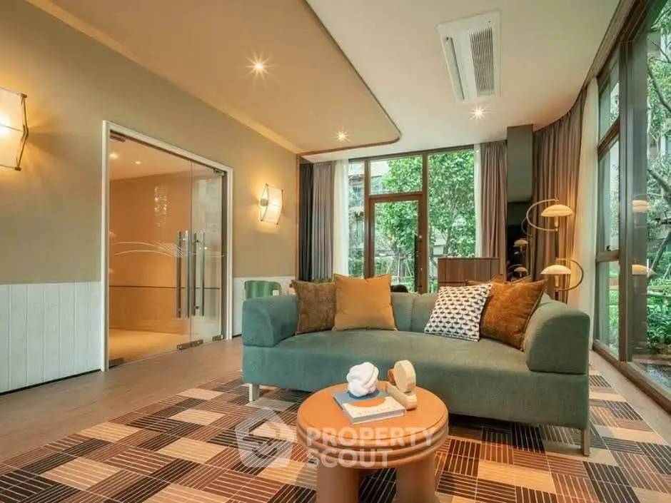 Spacious living room with modern decor and large windows overlooking greenery.