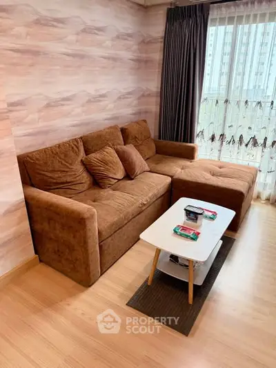 Cozy living room with brown sectional sofa and modern coffee table, featuring large window with city view.