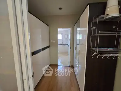 Spacious hallway leading to a modern bathroom with sleek storage solutions.