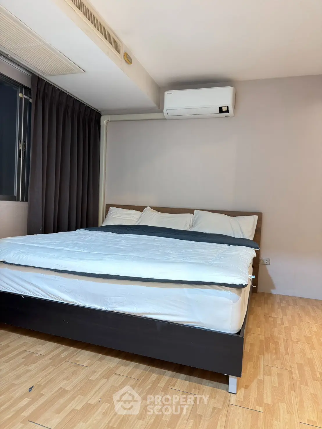 Spacious bedroom with modern air conditioning and elegant wooden flooring